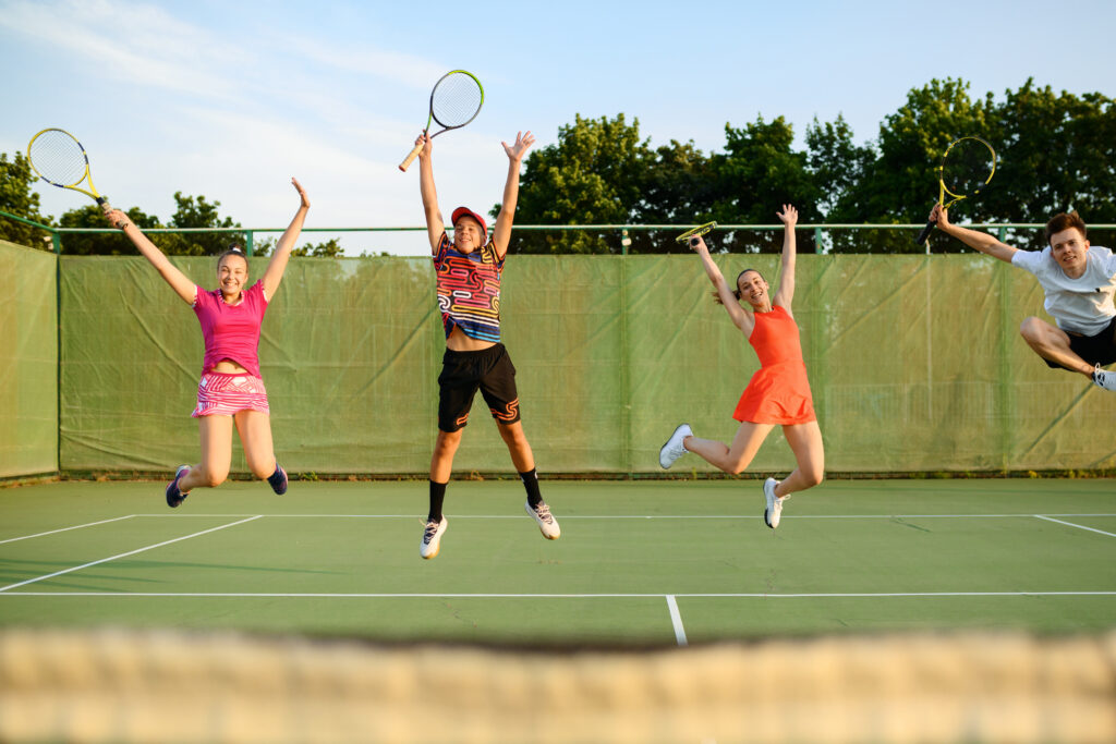 Brother and sister smiling together on a tennis court